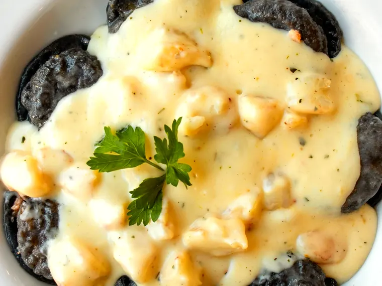 Ravioles negros con salsa de mariscos.